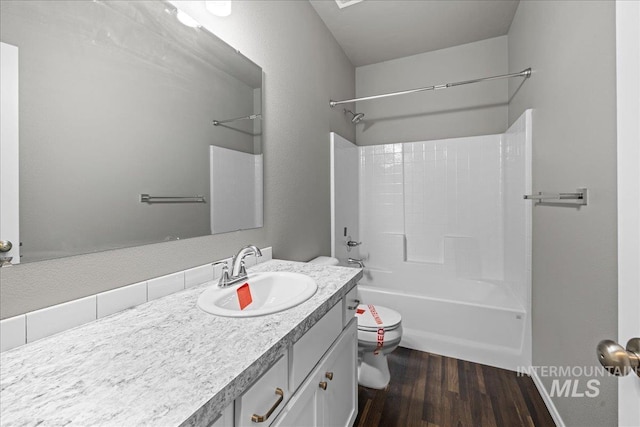 full bathroom featuring hardwood / wood-style flooring, vanity, washtub / shower combination, and toilet