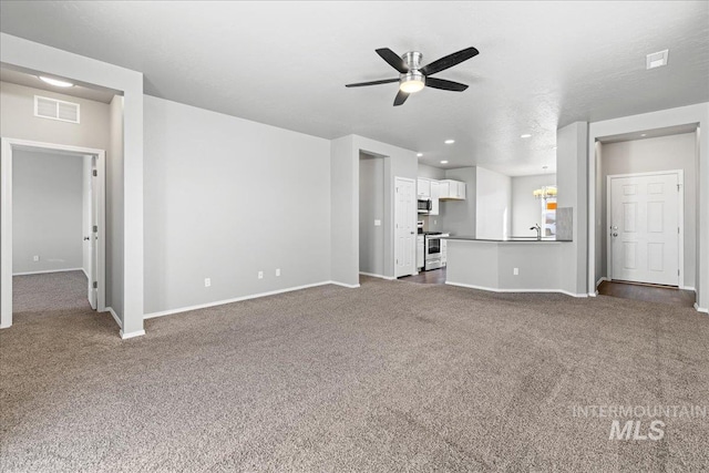 unfurnished living room with ceiling fan, sink, and dark colored carpet