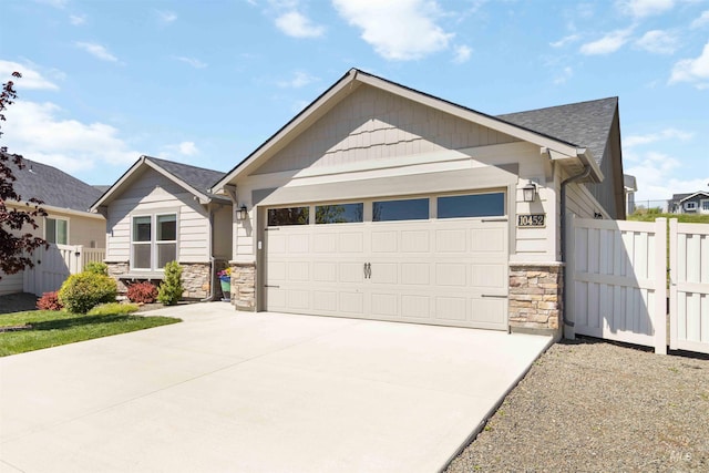 craftsman house with stone siding, a garage, fence, concrete driveway, and a shingled roof