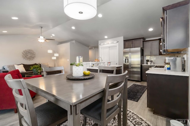 dining space with light wood-style flooring, ceiling fan, vaulted ceiling, and recessed lighting
