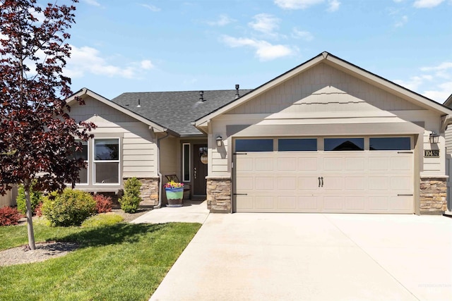 view of front facade with stone siding, a garage, driveway, a shingled roof, and a front lawn