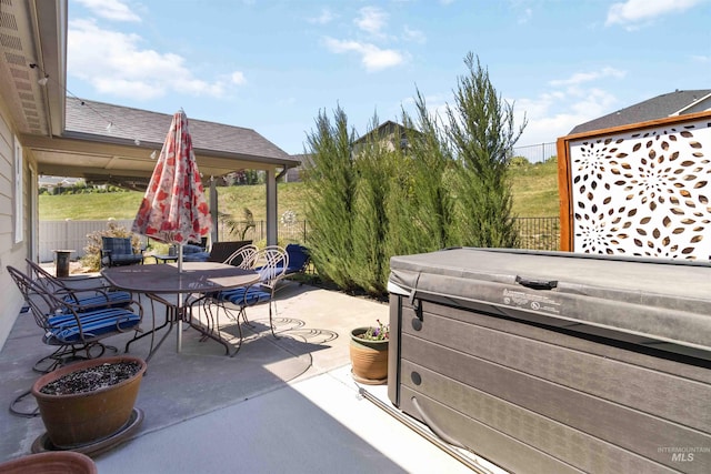 view of patio with a hot tub, outdoor dining area, and fence