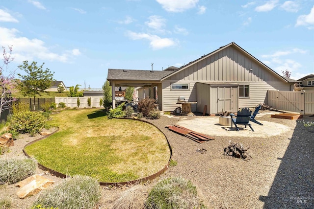 back of house with board and batten siding, a patio area, a gate, and an outdoor fire pit