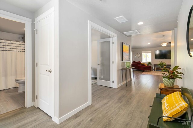hallway featuring light wood finished floors, recessed lighting, and baseboards