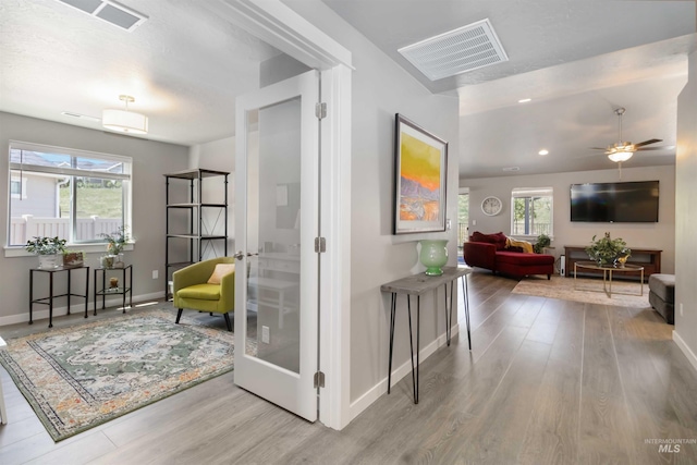 hallway with wood finished floors, plenty of natural light, baseboards, and recessed lighting