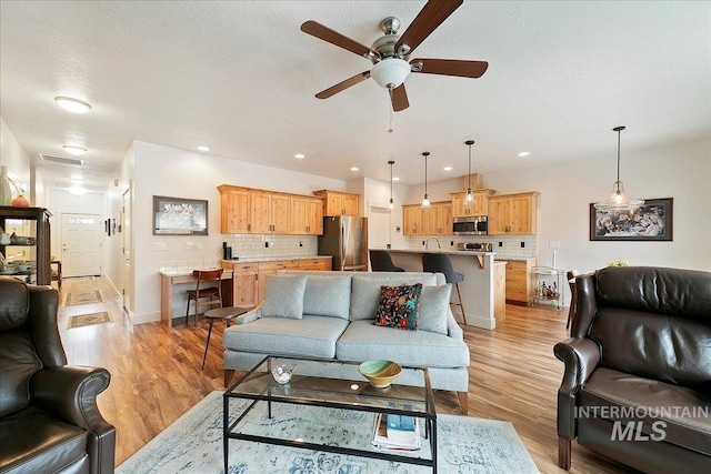 living room with a ceiling fan, recessed lighting, light wood-style floors, and visible vents