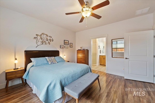 bedroom with a ceiling fan, wood finished floors, baseboards, and ensuite bathroom