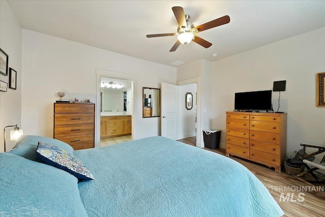 bedroom with light wood-type flooring, ensuite bath, and a ceiling fan