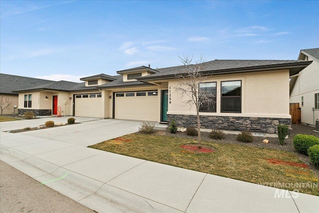 prairie-style house featuring stone siding, stucco siding, an attached garage, and concrete driveway