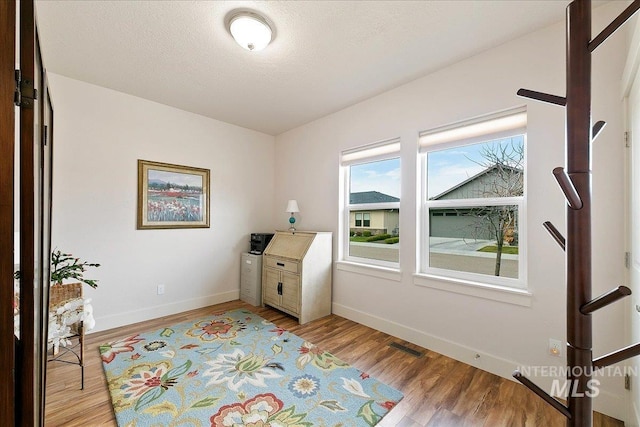 office area featuring baseboards, a textured ceiling, and light wood-style flooring