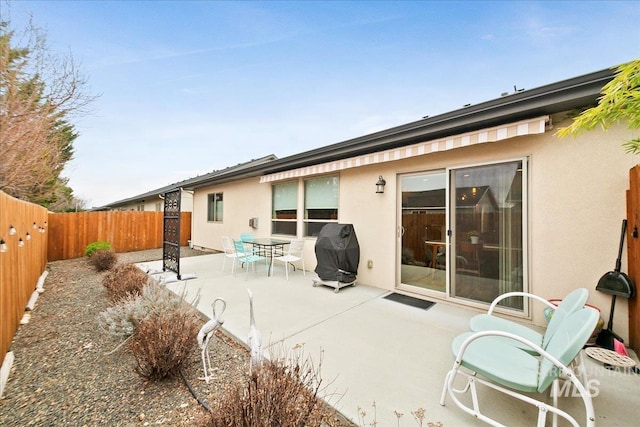 rear view of property with stucco siding, a patio, and a fenced backyard