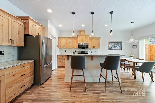 kitchen featuring light brown cabinetry, appliances with stainless steel finishes, and light wood-style floors