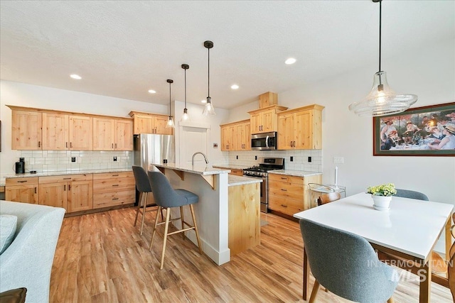 kitchen with light brown cabinets, light wood-style floors, and appliances with stainless steel finishes