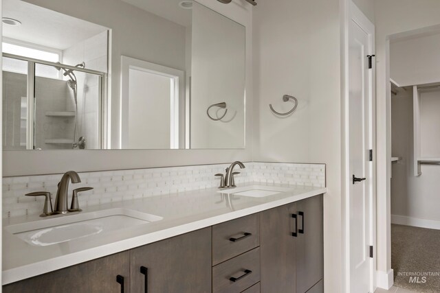 bathroom with walk in shower, vanity, and backsplash