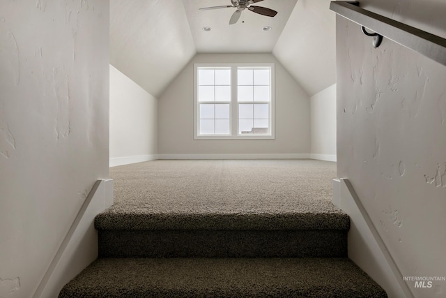 stairway featuring vaulted ceiling, ceiling fan, and carpet flooring