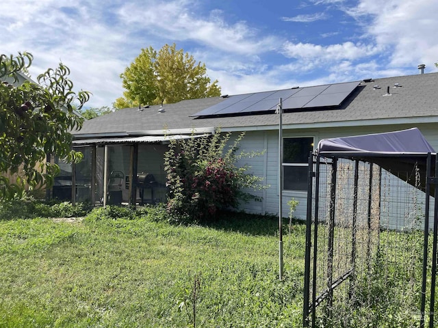 14285 Shenandoah St, Caldwell, ID 83607 - back of property featuring a sunroom, solar panels, roof with shingles, and a yard