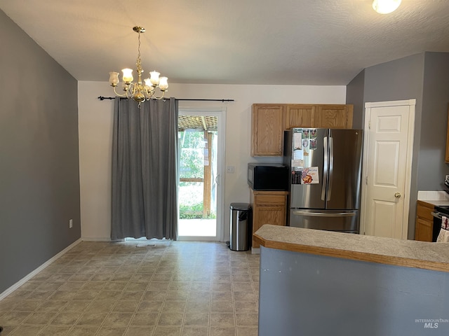 14285 Shenandoah St, Caldwell, ID 83607 - kitchen featuring freestanding refrigerator, a chandelier, pendant lighting, brown cabinetry, and light countertops