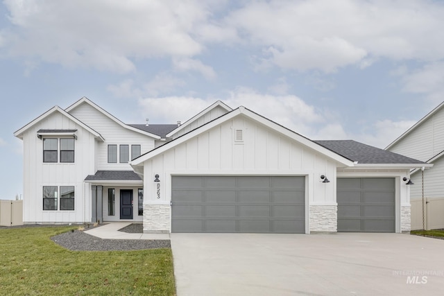 modern farmhouse featuring a garage, stone siding, board and batten siding, and concrete driveway