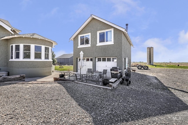 133 N Rd, Jerome, ID 83338 - rear view of house with a patio, a detached garage, and stucco siding