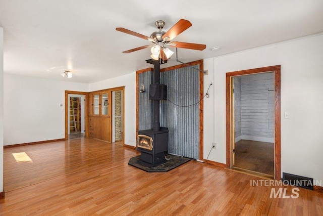 1045 N Beech Rd, Genesee, ID 83832 - unfurnished living room with a wood stove, light wood-style flooring, baseboards, and ceiling fan