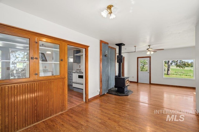 1045 N Beech Rd, Genesee, ID 83832 - unfurnished living room with a wood stove, baseboards, a ceiling fan, and wood finished floors