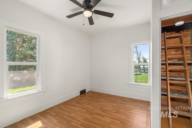 1045 N Beech Rd, Genesee, ID 83832 - empty room featuring crown molding, visible vents, wood finished floors, and a healthy amount of sunlight