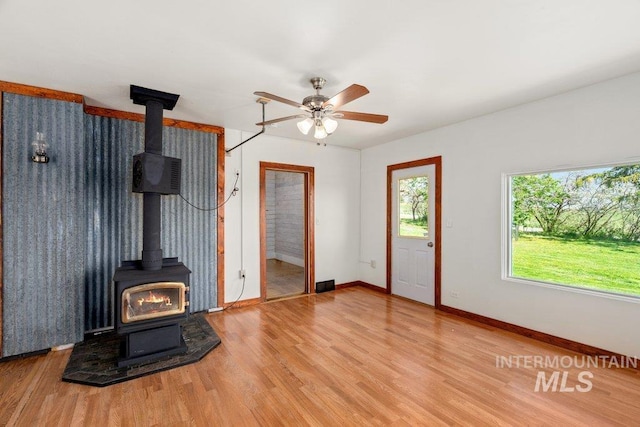 1045 N Beech Rd, Genesee, ID 83832 - unfurnished living room featuring a wood stove, wood finished floors, baseboards, and ceiling fan