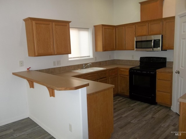 kitchen with dark hardwood / wood-style floors, black electric range oven, a breakfast bar area, sink, and kitchen peninsula