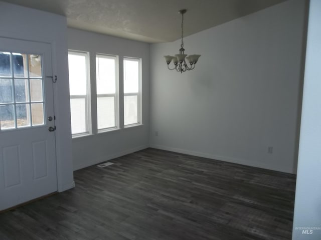 unfurnished dining area featuring dark hardwood / wood-style floors and a chandelier