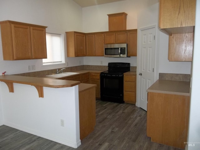 kitchen with dark hardwood / wood-style floors, black electric range, a kitchen breakfast bar, and kitchen peninsula