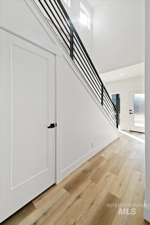 stairs with hardwood / wood-style floors and a towering ceiling