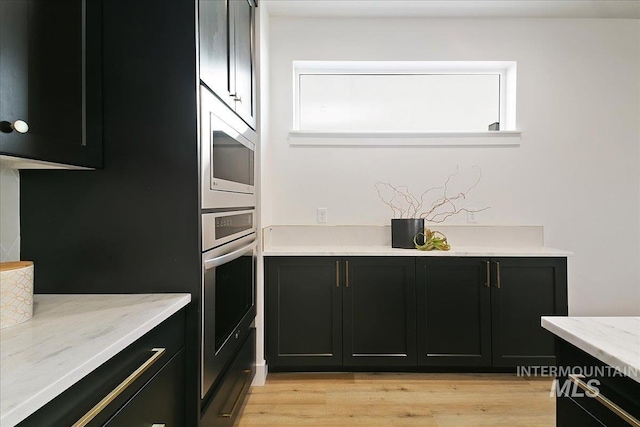 kitchen featuring light stone counters, light wood-type flooring, and appliances with stainless steel finishes