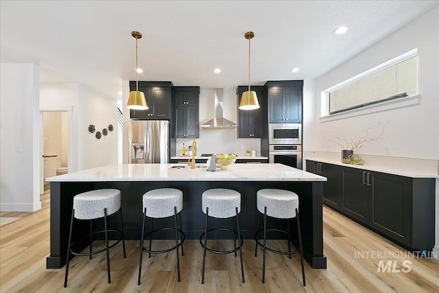 kitchen featuring stainless steel appliances, an island with sink, and wall chimney range hood