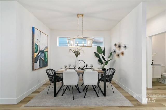 dining space with a notable chandelier and light hardwood / wood-style floors