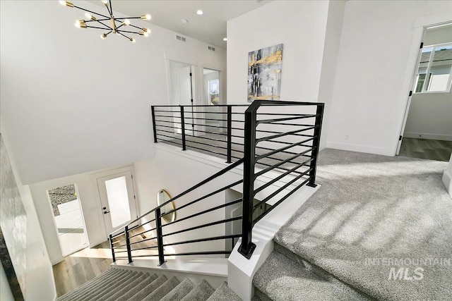 staircase featuring a notable chandelier and carpet