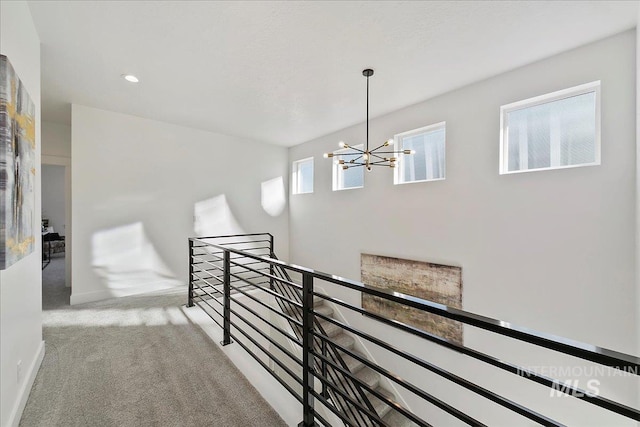 hall featuring an inviting chandelier and carpet flooring