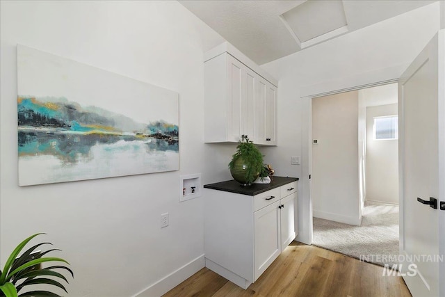 clothes washing area with cabinets, washer hookup, and light hardwood / wood-style flooring