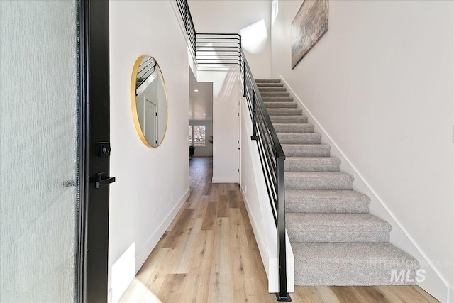 stairway with a towering ceiling and wood-type flooring