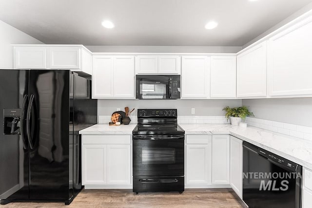 kitchen with black appliances, light stone counters, and white cabinets