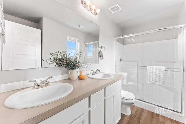 bathroom with toilet, visible vents, a sink, and wood finished floors