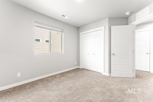 unfurnished bedroom with visible vents, a closet, baseboards, and carpet flooring