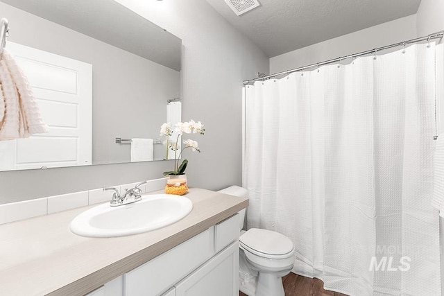 bathroom featuring visible vents, toilet, a shower with curtain, wood finished floors, and vanity