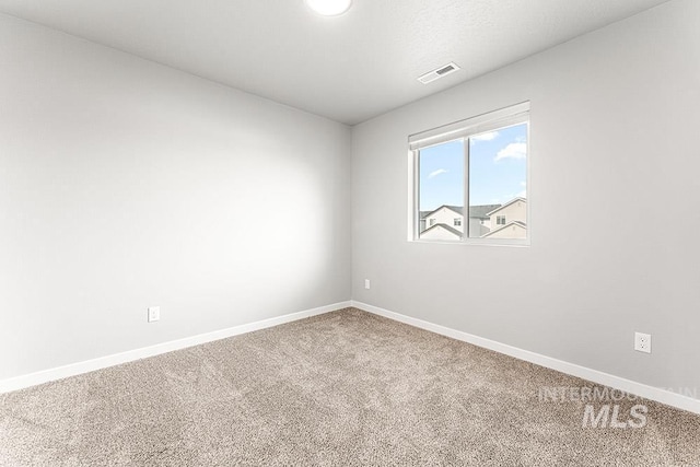 carpeted spare room with visible vents and baseboards