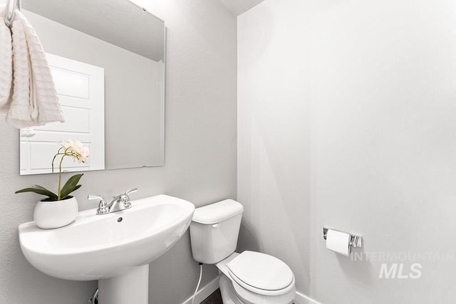 bathroom with baseboards, a sink, and toilet