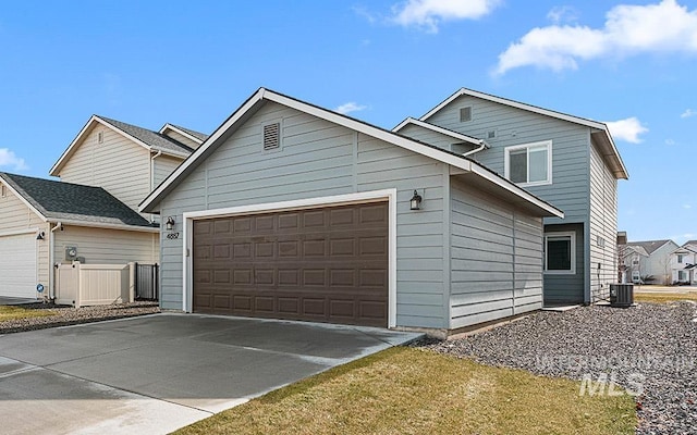 view of front of property featuring concrete driveway, an attached garage, and cooling unit