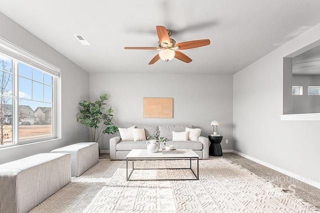 carpeted living area with a ceiling fan, visible vents, and baseboards