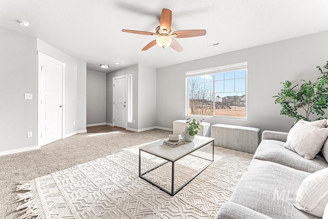 carpeted living area featuring a ceiling fan, visible vents, and baseboards