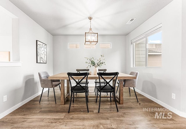 dining room with baseboards, visible vents, a chandelier, and wood finished floors