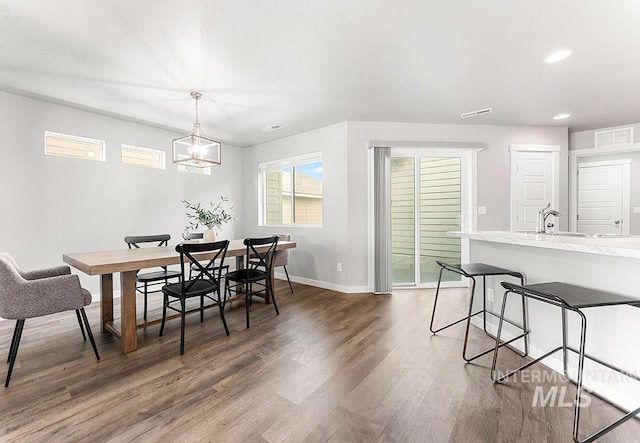 dining area featuring baseboards, visible vents, wood finished floors, an inviting chandelier, and recessed lighting