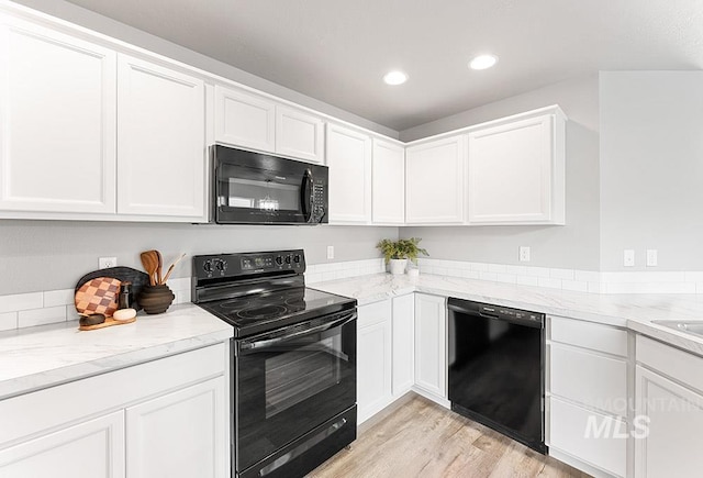 kitchen featuring light stone countertops, light wood-type flooring, black appliances, white cabinetry, and recessed lighting